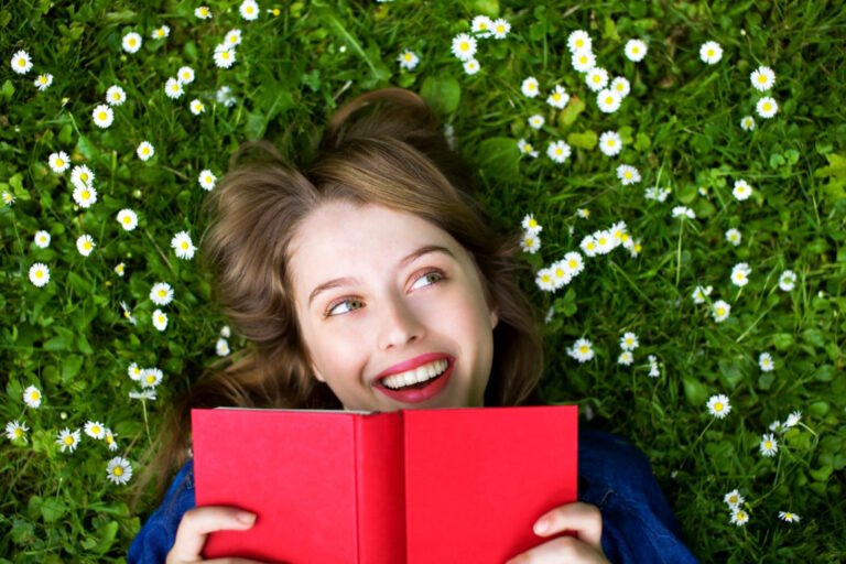 woman reading a book outside in the grass